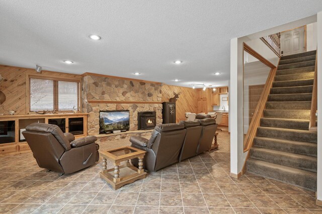 living area with wooden walls, stairway, a fireplace, and a textured ceiling