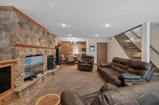 living room featuring a textured ceiling, recessed lighting, stairs, ornamental molding, and a wood stove