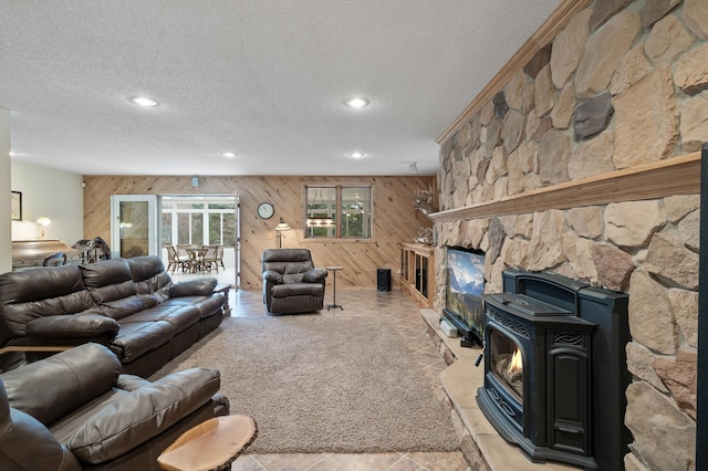 living area with a textured ceiling, recessed lighting, a wood stove, and wooden walls