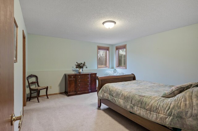 bedroom with light colored carpet, a textured ceiling, and baseboards