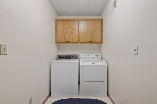 laundry room with washer and clothes dryer, visible vents, cabinet space, light tile patterned flooring, and baseboards