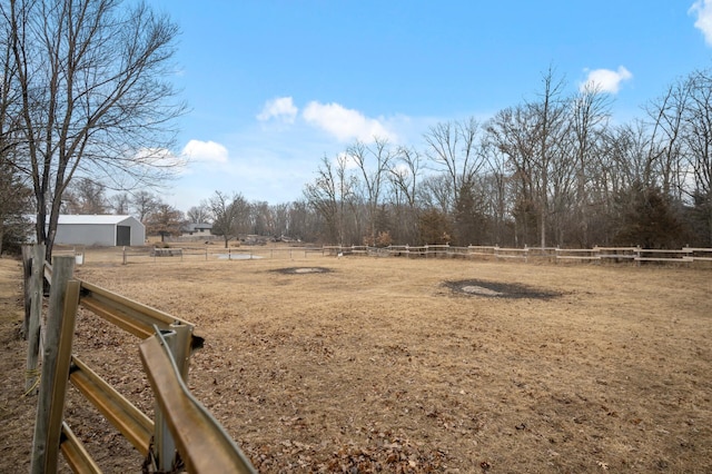 view of yard with a rural view, fence, and an outbuilding