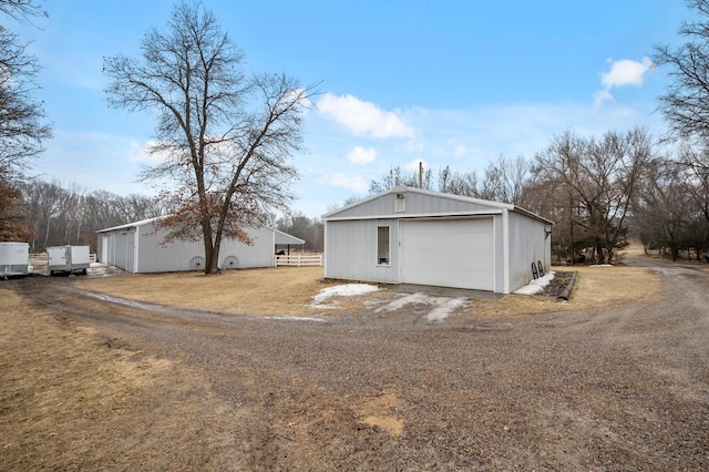 rear view of house with a garage, driveway, an outdoor structure, and an outbuilding