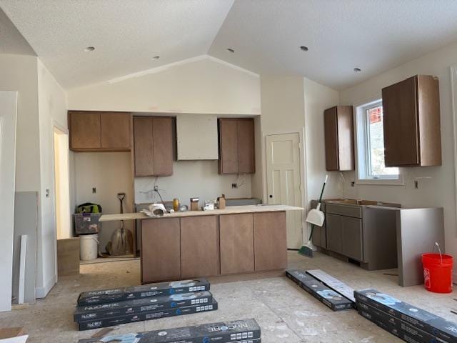 kitchen featuring vaulted ceiling and wall chimney exhaust hood