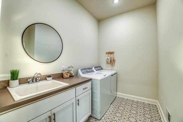 laundry area featuring light tile patterned flooring, sink, washer and clothes dryer, and cabinets