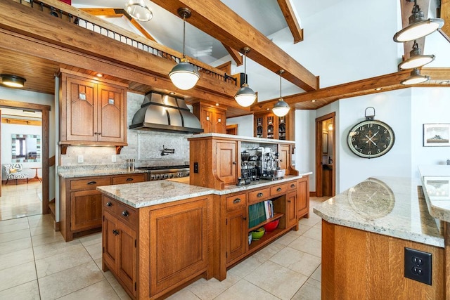 kitchen with brown cabinets, decorative light fixtures, a kitchen island, light stone countertops, and wall chimney exhaust hood