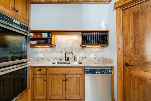 kitchen with appliances with stainless steel finishes, brown cabinets, a sink, and tasteful backsplash