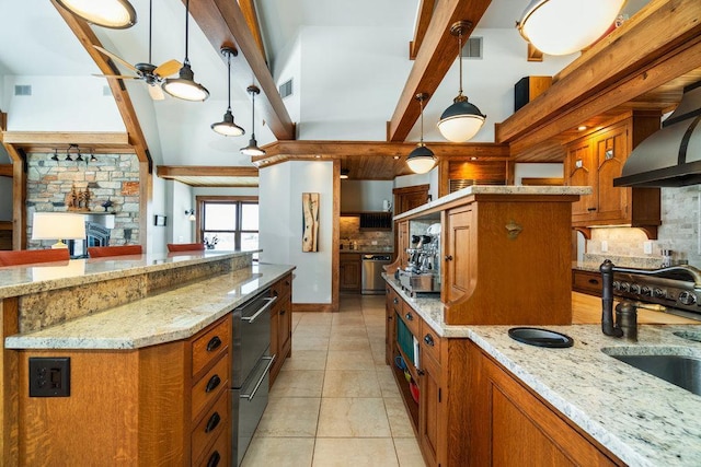 kitchen featuring pendant lighting, a spacious island, brown cabinetry, a sink, and light stone countertops