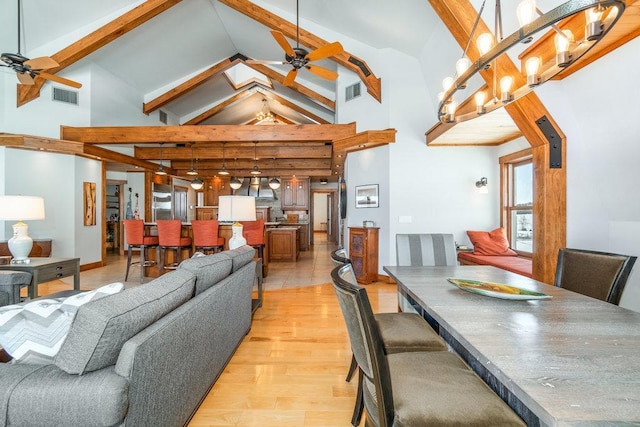 dining space featuring ceiling fan, high vaulted ceiling, light wood finished floors, and visible vents