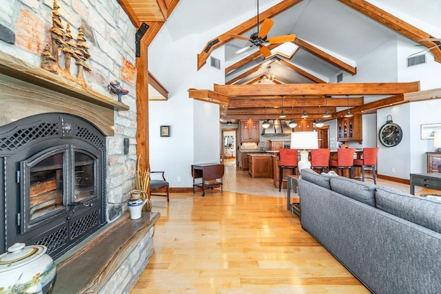 living room featuring high vaulted ceiling, visible vents, a ceiling fan, light wood-type flooring, and beamed ceiling