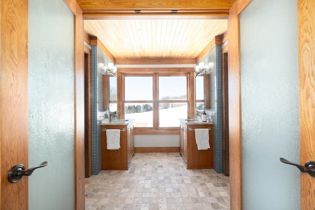 corridor with a textured wall, a sink, and wood ceiling