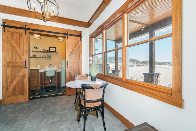 dining space featuring a barn door, baseboards, a notable chandelier, and ornamental molding