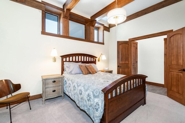 bedroom featuring baseboards, beamed ceiling, and light colored carpet