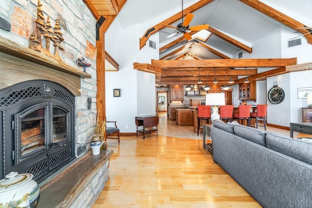 N7900 County Road J, Sherman Twp, WI 54751 - living area featuring high vaulted ceiling, ceiling fan, beamed ceiling, a stone fireplace, and light wood finished floors