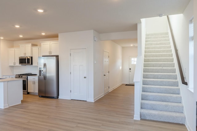 kitchen with white cabinets, light hardwood / wood-style flooring, and stainless steel appliances