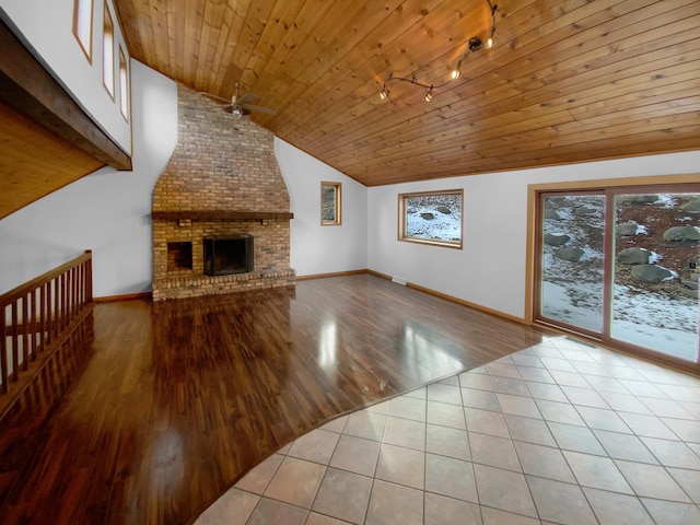 unfurnished living room featuring track lighting, wood ceiling, vaulted ceiling, light tile patterned floors, and a brick fireplace