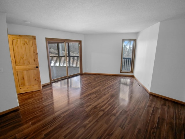 spare room featuring dark wood-type flooring and a textured ceiling