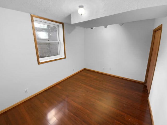 unfurnished room with a textured ceiling and dark hardwood / wood-style floors