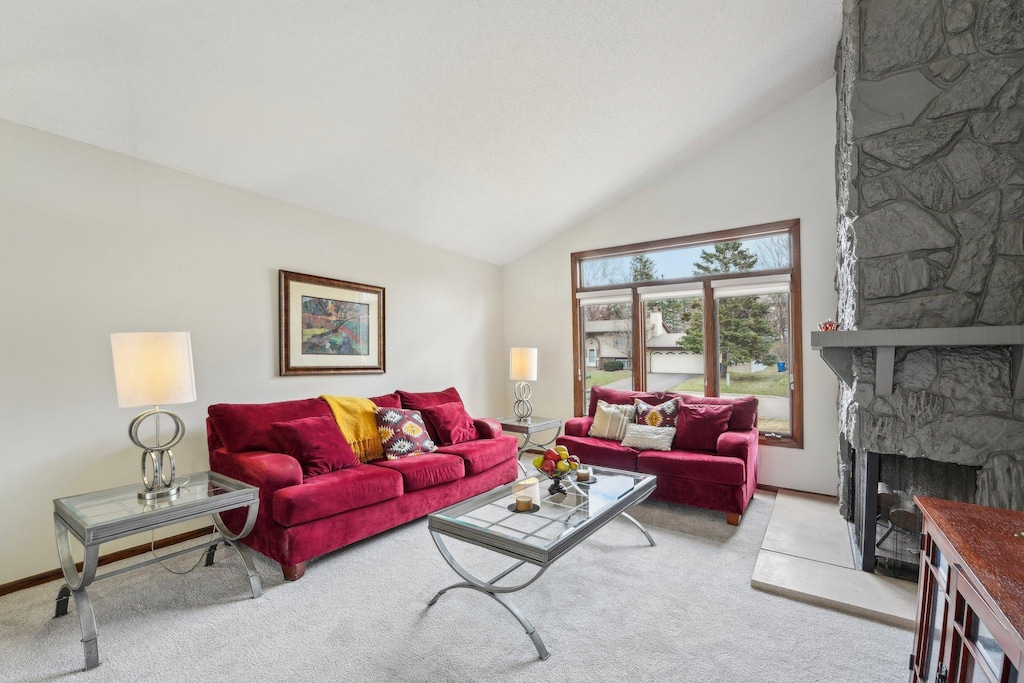 living area with a fireplace, carpet flooring, and vaulted ceiling