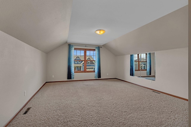 additional living space featuring lofted ceiling, baseboards, visible vents, and carpet flooring