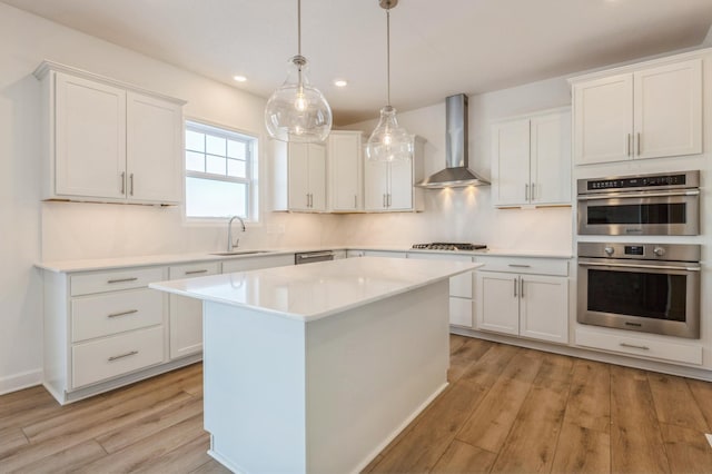 kitchen featuring sink, wall chimney range hood, white cabinets, and a center island