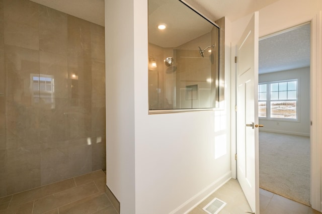 bathroom with a tile shower and tile patterned flooring