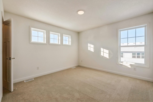 spare room with light carpet and a textured ceiling