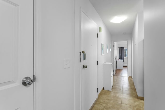 hallway with baseboards and light tile patterned floors