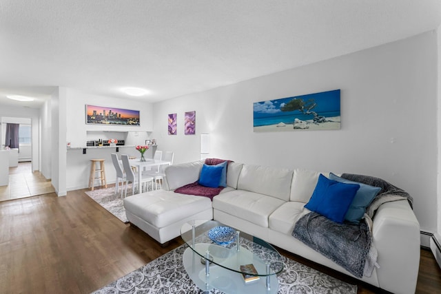 living room with a textured ceiling, a baseboard heating unit, and wood finished floors