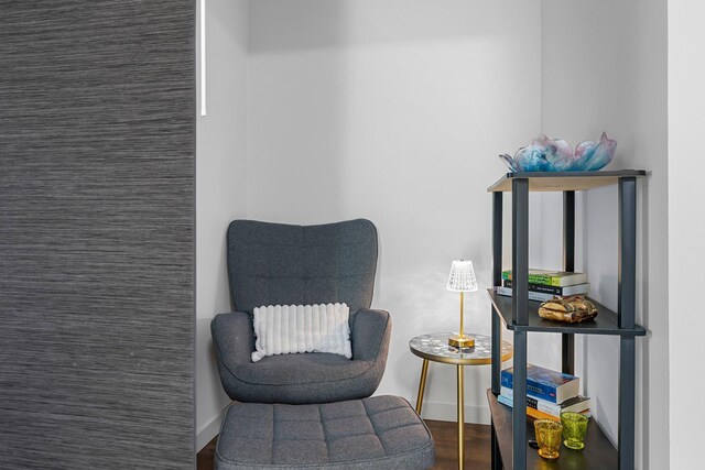 sitting room with an accent wall and wood finished floors