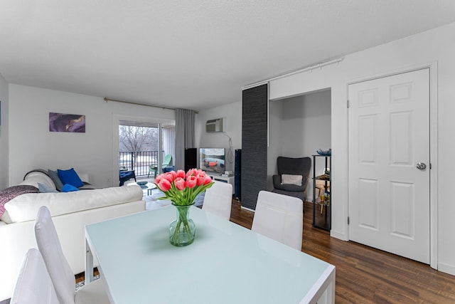 dining area with dark wood-style flooring and a wall unit AC