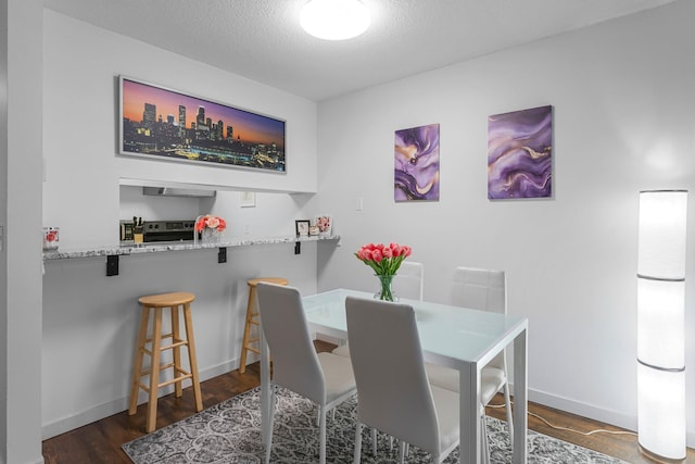 dining room with dark wood-style floors, baseboards, and a textured ceiling