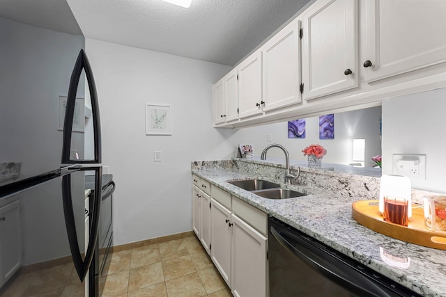 kitchen featuring white cabinets, dishwasher, freestanding refrigerator, light stone countertops, and a sink