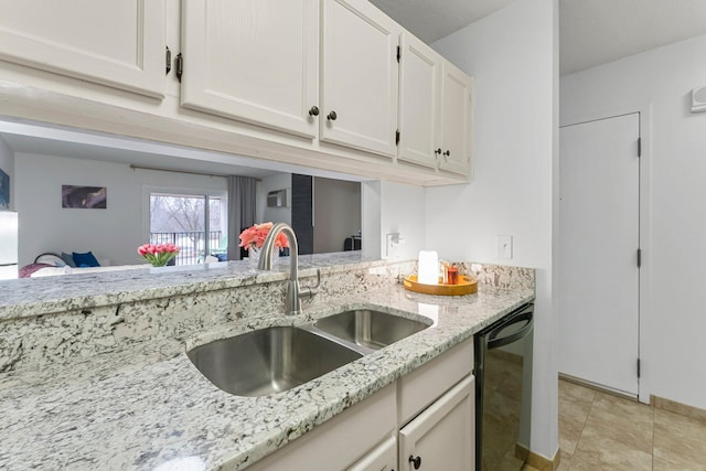 kitchen with light tile patterned floors, black dishwasher, white cabinets, light stone counters, and a sink