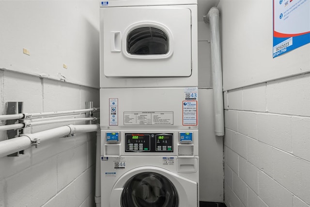 laundry area with stacked washer and dryer and concrete block wall