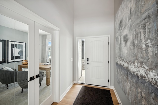 foyer entrance with light wood finished floors, french doors, and baseboards