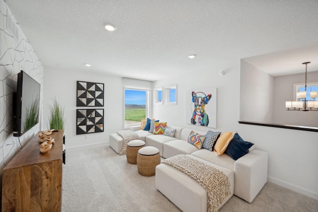 living area featuring a textured ceiling, an inviting chandelier, baseboards, and light colored carpet