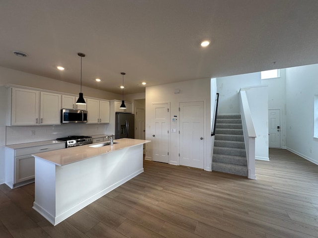 kitchen featuring visible vents, an island with sink, a sink, white cabinetry, and stainless steel appliances