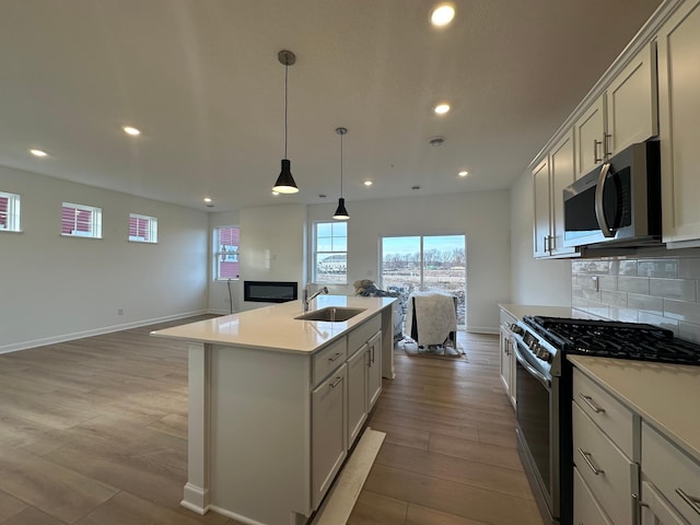 kitchen with a sink, open floor plan, stainless steel appliances, light countertops, and decorative backsplash