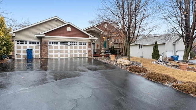 view of front of property featuring aphalt driveway, stone siding, and an attached garage