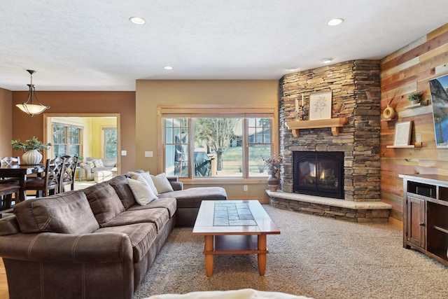 carpeted living room featuring a textured ceiling and a stone fireplace