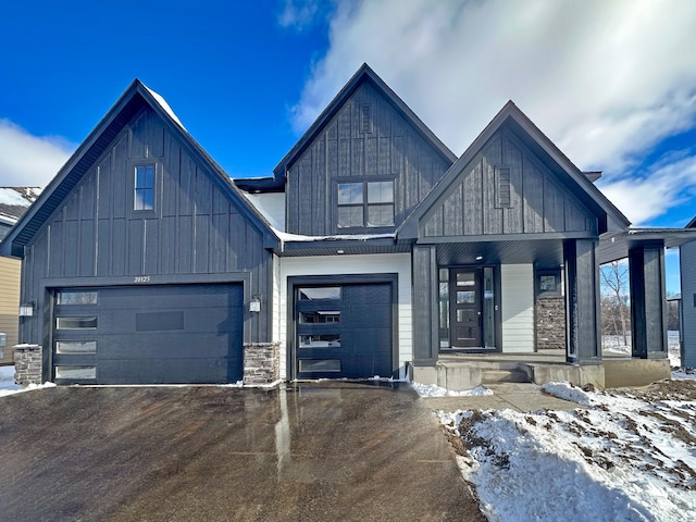 modern inspired farmhouse featuring an attached garage, a porch, aphalt driveway, and board and batten siding