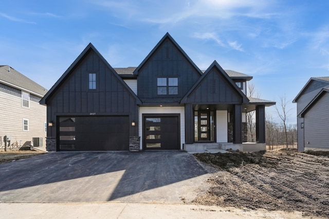 modern farmhouse with a garage, central AC unit, board and batten siding, and driveway