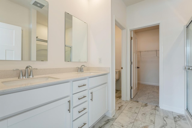 bathroom featuring toilet, vanity, and a shower with door