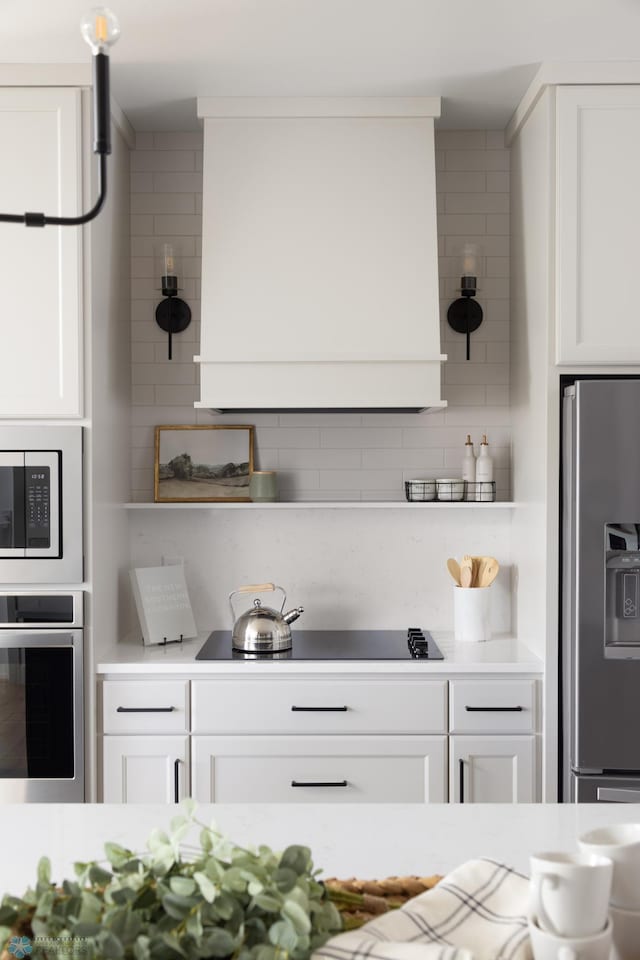 interior space with white cabinets, stainless steel appliances, and decorative backsplash