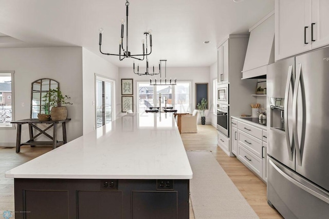 kitchen featuring white cabinets, stainless steel appliances, pendant lighting, and a center island