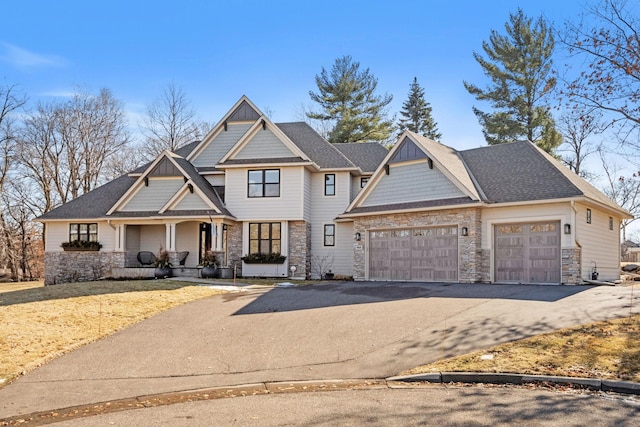 view of front of home featuring an attached garage, stone siding, aphalt driveway, and board and batten siding