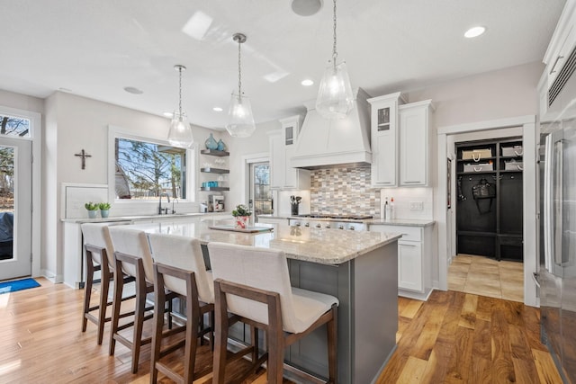 kitchen with a wealth of natural light, custom range hood, stainless steel gas stovetop, and a kitchen breakfast bar