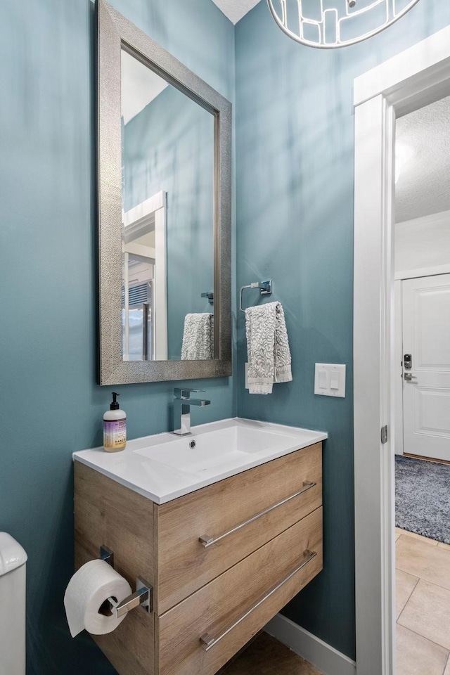 bathroom featuring toilet, vanity, baseboards, and tile patterned floors