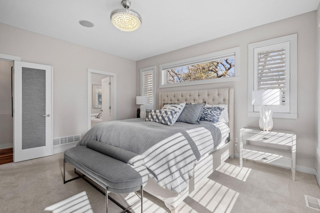 carpeted bedroom with multiple windows, connected bathroom, visible vents, and baseboards